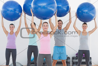 Fitness class holding up exercise balls at the fitness studio