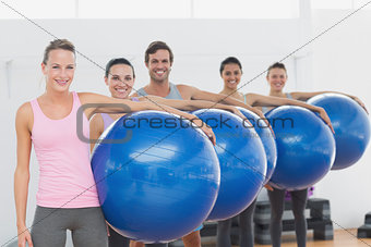 Fitness class holding exercise balls at fitness studio