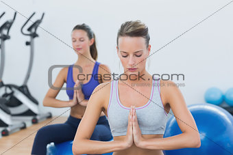 Women with joined hands and eyes closed on exercise balls