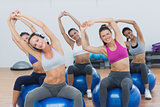 Sporty women stretching up hands on exercise balls at gym