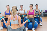 Fit class exercising with dumbbells on fitness balls