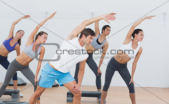Class doing stretching exercise in fitness studio