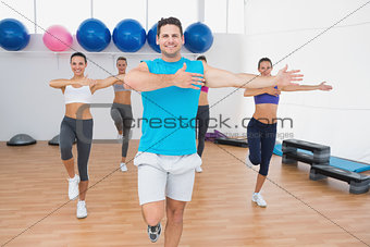 Smiling people doing power fitness exercise in fitness studio