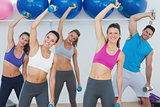 Portrait of fitness class exercising with dumbbells