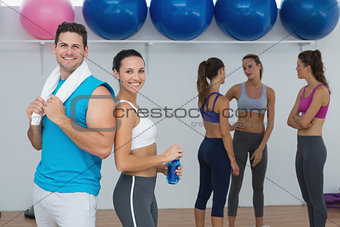 Smiling couple with fitness class in background