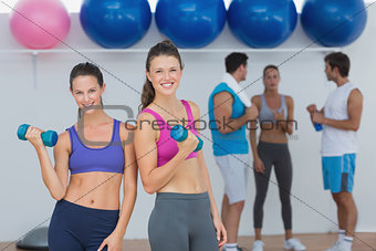 Fit women holding dumbbells with class in background