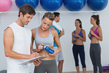 Couple looking at clipboard with fitness class in background