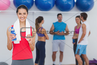 Female holding water bottle with fitness class in background