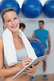 Trainer holding clipboard with fitness class in background