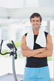 Smiling man with arms crossed at spinning class in bright gym