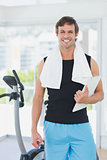 Smiling male trainer with clipboard in bright gym