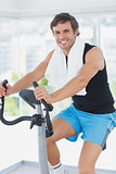 Smiling man working out at spinning class in bright gym