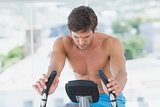 Determined man working out at spinning class in bright gym