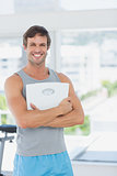 Fit man standing with scale in bright exercise room
