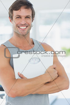 Fit young man with scale in bright exercise room