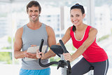 Woman with instructor working out at spinning class in bright gym