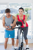 Fit woman with male instructor working out at spinning class