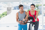 Woman with male instructor working out at spinning class