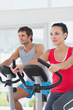 Determined couple working out at spinning class in gym