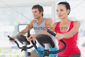 Determined couple working out at spinning class in gym