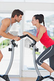 Determined couple working out at spinning class