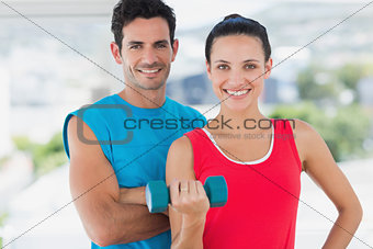Fit couple with dumbbell in bright exercise room