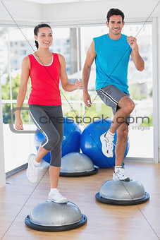 Couple performing on dome balance in gym
