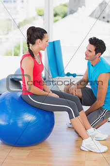 Instructor and woman with exercise ball at gym