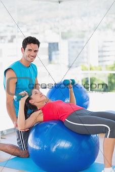 Trainer helping woman with her exercises at gym