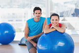 Instructor and smiling woman with exercise ball at gym