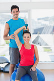 Male trainer helping woman with her exercises at gym