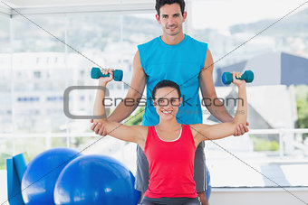 Male trainer helping woman with her exercises at gym