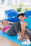 Trainer helping woman with her exercises at gym