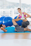 Female trainer helping man with his exercises at gym