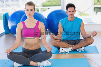 Young couple sitting in lotus posture at fitness studio
