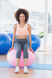 Portrait of a fit woman sitting on fitness ball at gym