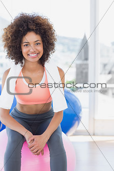 Fit young woman sitting on fitness ball at gym