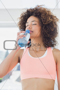 Fit female drinking water at gym