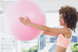Sporty young woman holding ball in fitness studio