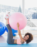 Sporty young woman with exercise ball in fitness studio