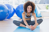 Fit woman doing the butterfly stretch in exercise room