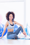 Fit young woman sitting on exercise mat in fitness studio
