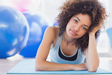 Fit woman lying on exercise mat in fitness studio