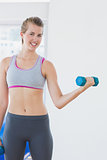 Young woman exercising with dumbbell in fitness studio