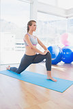 Fit woman stretching leg in fitness studio