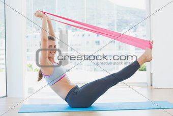 Sporty young woman with exercise band in fitness studio