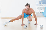 Sporty shirtless man exercising in fitness studio