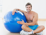 Shirtless man with fitness ball in gym