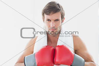 Serious young man in red boxing gloves