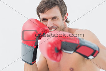 Portrait of a smiling young man in red boxing gloves